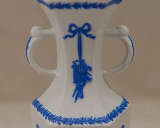 Closeup of antique c. 1820 Wedgwood white jasper two-handled vase with applied blue sprig classical Greek figures and both arts and military symbols decoration. Stamped Wedgwood to the base – each letter individually stamped in —and a blue sprig oval embossed "pad mark" showing the numerals 979 for the shape number.