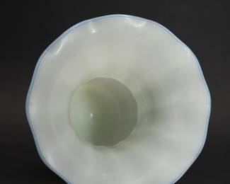 Another view of the early 20th century (circa 1920-1933) American hand blown Steuben art glass vase made from luminous iridized Ivrene glass in shape #7565, a documented design by Steuben Glass Works co-founder Frederick Carder. The bulbous form sits on a narrow dome base, the neck with flaring optic ribs and graceful scalloped rim that has a narrow applied edge of light blue glass. Marked "Steuben" in script on underside of base. 9 inches wide x 10 inches high. 