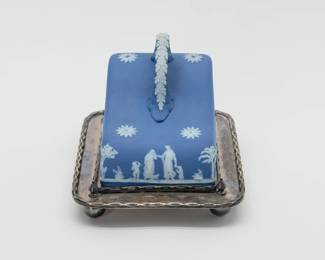 Another view of the early 20th Century Wedgwood cheese dome of blue Jasperware with its original silverplated tray. The blue dome with white classical figures including Cupid and Diana with stag in bas-relief, the applied handle with white acanthus leaves. Marked to the inside with WEDGWOOD and MADE IN ENGLAND. The silverplated tray is original to the cheese dome set, and is raised on ball feet; hallmarks to the underside are from H. Fisher & C, silversmiths in Sheffield, England.
