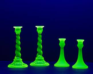 Seen under blacklight: Pair of Northwood yellow uranium glass spiral twist candlesticks circa 1920's, and pair of Tiffin Glass Canary Satin vaseline uranium glass candlesticks, circa 1920s 