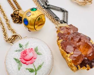 Closeup of some of the pendant necklace costume jewelry including guillochet enameled lockets and Hessonite garnet cluster 