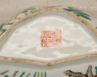 Closeup of a Chinese export porcelain polychrome enamel bowl in bat form with floral decoration including lotus, chrysanthemum, peony, plum blossoms; six-character mark on base.