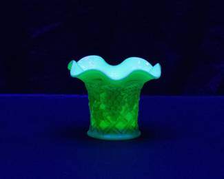 Seen under black light: A Northwood Grape Arbor pattern Nutmeg Stain custard glass uranium glass vase