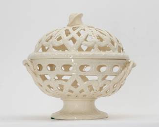 A late 19th century antique Wedgwood cream ware footed “orange bowl” and cover, beautifully crafted with symmetrical pierced lattice work, garland and foliate scrolls with applied twisted rope handles and a flower finial. 10” high x 9” wide. Impressed Wedgwood stamp beneath the circular foot. 

Orange Bowls were used in the 17th & 18th centuries when oranges were also used to give a room the delightful scent of oranges. Creamware was developed by Josiah Wedgewood in 1762. It was later dubbed "Queen's ware" after Queen Charlotte was delighted to receive a Cream Ware tea set in 1766 — following that Josiah Wedgwood was awarded the honor of “Potter to Her Majesty.”