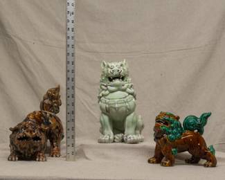 Three Chinese porcelain large figures of foo dogs or temple lions, the largest one in a pale celadon green glaze with brown accents, one in a rich mottled brown and black glaze, and one in a warm brown and vivid green glaze