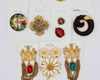 Colorful classy vintage costume jewelry brooches including United Kingdom heraldic lion and unicorn brooches, a gold tone fleur de lis set with rhinestones, a carved amber brooch and vintage enameled daisy earrings and brooch set
