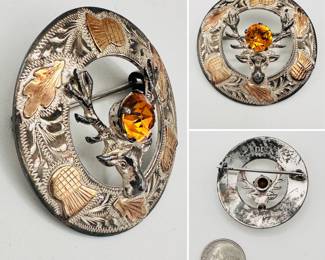 Vintage Scottish sterling silver brooch, engraved with thistle flowers and leaves highlighted with applied gold; the center with a dimensional stag's head supporting a faceted citrine gem. Hallmarked to the back with sterling silver, and Glasgow silversmiths Ward Brothers Scotland, date stamp for 1953.
