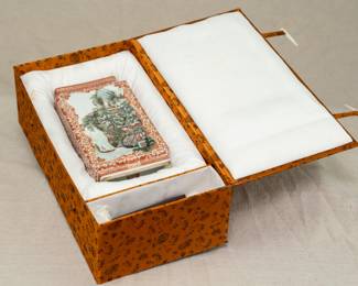 Seen in its padded case, a Chinese rectangular vase dating from the 1950s with wooden stand. Vase features a coral red lotus and flower tracery ground and 2 famille rose enameled landscape scenes on the front and back. The bottom of the vase has a 4-character mark.