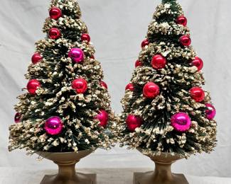 A pair of tabletop Christmas trees with gold finish metal bowl stands, flocked snow and shiny red and pink ornaments