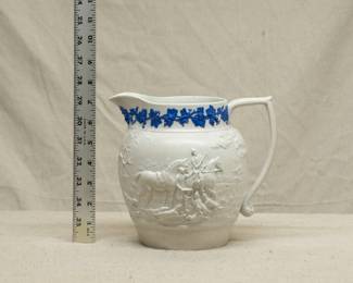 An early 19th century Wedgwood smear glazed white pitcher decorated with finely modeled jasper applied to depict a hunting scene, and with dark blue jasper grapevines applied around the top rim