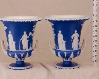 A pair of antique large Wedgwood dark blue dip jasperware double-handled urn shaped vases adorned with neoclassical decoration. Impressed 'WEDGWOOD' mark on the base.
