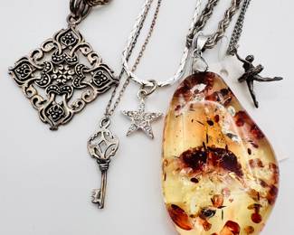 Closeup of some of the stylish pendant necklaces available, silvery tone chain necklaces with antique key charms, faux amber, figural charms