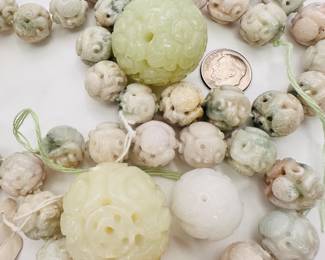 Closeup of a a string of carved jadite beads and larger loose carved jadite beads