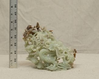 A large Chinese jade finely carved and reticulated two-horned dragon sculpture, the dragon battling for the "pearl of wisdom" amidst a dense network of cloud scrolls.