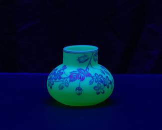 Seen under blacklight: Antique Harrach or Thomas Webb & Sons cameo glass vase circa 1890, cased blue over creamy white uranium glass, cameo cut around the body with flowering petals on leafy vines. A banded blue rim at the top and a polished pontil on the base.
