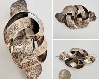 A charming antique sterling silver brooch in the form of curling ribbons, engraved with floral scroll work; hallmarked sterling silver, made in Birmingham, England in the 19th century.