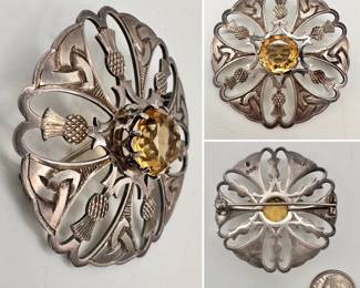 A high quality vintage sterling silver Scottish brooch, circular cutout frame with thistles and Celtic trinity knots, a raised faceted citrine set as a center stone. Hallmarks on the back include a thistle, an Edinburgh stamp, maker's mark of entwined JH for John Hart, silversmith; and the word "IONA"