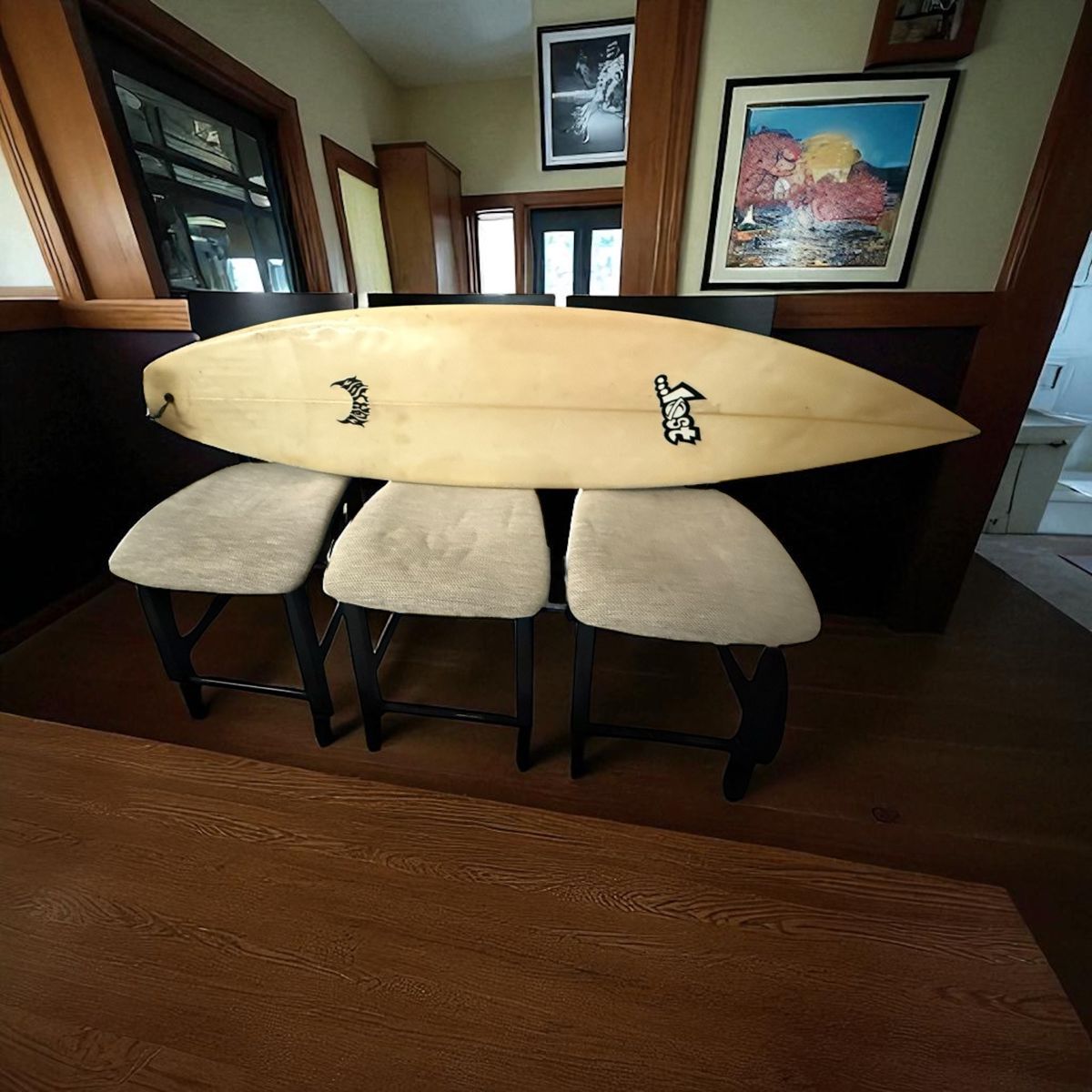 Three barstool height, stools, one surfboard
