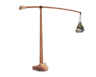 125
Harold Greene (b. 1953)
A Contemporary cantilevered floor lamp, 2014
The lacewood standard issuing a cantilevered arm with hammered copper hardware, one end featuring a handkerchief mottled glass shade over a single light, the other with a stone counterweight, all set in a stone base, electrified
Dimensions variable: 55.75" H x 57.5" W x 15" D
Estimate: $600 - $800