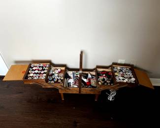 A treasure trove of sewing supplies, including a large assortment of threads in a standing vintage wooden sewing box.