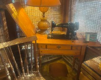 Singer sewing machine in cabinet and chair. Vintage lamp