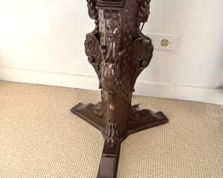 Close-Up of Ornate Carved Female Figure Pedestal on Antique Wood Table