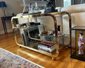 L3 - $750. Milo Baughman Brass and Glass 3 Tier Bar Cart. Measures 46.5" x 18" x 28" tall. The bottom right piece of glass has a chip we didn't notice until we were looking at it for issues. The glass could be replaced but if there is something near it you can't see it. 