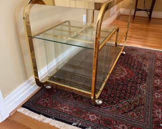 L3 - $750. Milo Baughman Brass and Glass 3 Tier Bar Cart. Measures 46.5" x 18" x 28" tall. The bottom right piece of glass has a chip we didn't notice until we were looking at it for issues. The glass could be replaced but if there is something near it you can't see it. 