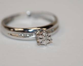 10kt white gold Diamond Ring that features a central small round diamond with 3 additional diamonds on each shoulder total weight for all 7 diamonds is approx .20ctw, size 5, 1.4 grams total weight