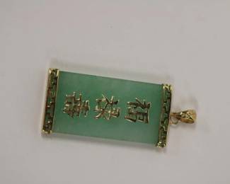 14kt yellow gold Green Jade Pendant that measures approx 1.5" long including bale and approx .50" wide pendant features applied gold writing down center and is framed in gold o top and bottom, 4.8 grams total weight