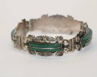 .925 Sterling Malacite Bracelet signed Mexico and features 4 heavily chased sterling panels each containing 2 curved sections of malacite divided by a strip of sterling measures approx 7", 26.1 grams with hidden box clasp