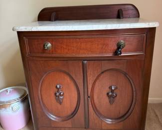 Cararra marble wash stand. Center compartment has a top drawer for storage space snd 2 shelves inside.  The 2 piece pink and gold trimmed croc matches other accessories of the ladies wash set. 