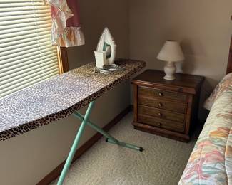 Ironing board and bedside table with lamp.