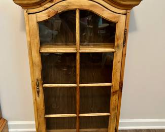 Rustic Glass-Front Wall Cabinet
Solid wood rustic wall cabinet with arched crown molding and six-pane glass-front door. Features decorative brass hardware and natural wood finish with visible grain. Perfect for farmhouse, cabin, or lodge-style décor—ideal for displaying books, collectibles, or kitchen items.