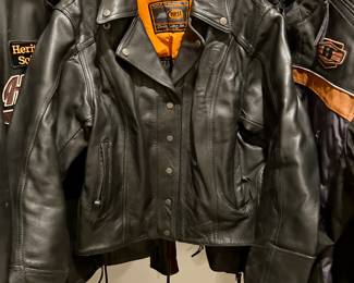 Premium First Classics black leather motorcycle jacket, heavy-weight genuine leather with orange quilted lining. Custom Harley-Davidson and American flag patches on back, classic side-laced design, zip cuffs, and snap-down lapels.