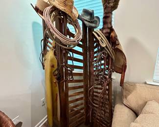 Western Saddle Rack with Vintage Cowboy Gear
Rustic wooden saddle/tack rack with an assortment of western décor and riding gear, perfect for display in a lodge, ranch home, or man cave. The rack holds a collection of cowboy hats, lassos, spurs, leather tack, and a vintage saddle holster with padlock. There’s even a classic coonskin cap for a true frontier feel.

This set makes a bold statement piece — whether used functionally for horse tack or decoratively as a western display.

Condition: Good rustic condition with authentic age and wear.

Dimensions: Approx. 40” W x 55” H x 24” D
