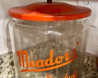 Vintage Meador’s Products Store Jar
Classic 1940s–50s advertising display jar with bright orange lettering and matching lid. Used in general stores and groceries to hold candy or baked goods. 