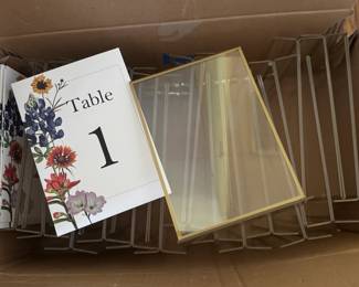 Gold-rimmed table number holders and custom Texas wildflower signs.