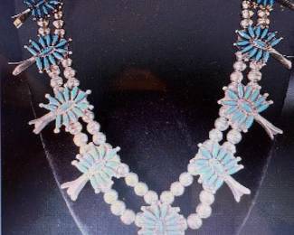 Turquoise Squash Blossom Necklace.
Maker: Norman & Virginia Hooie, Zuni.
Necklace is about 24 inches round. 
Total weight 100 g. Pictures do not do the jewelry justice. For more details go to: https://modestlambestatesales.hibid.com/