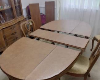 Close up view of dining table with protective table top padding and one of the three extension leaf inserts. The other two extension leaf inserts can be seen in the background.