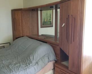 Storage headboard has closets, drawers; shelves and a mirror