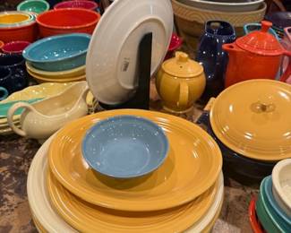 Fiesta Ware Dinnerware Set – Stacked yellow plates with blue bowl, assorted serving pieces, classic collectible pottery.