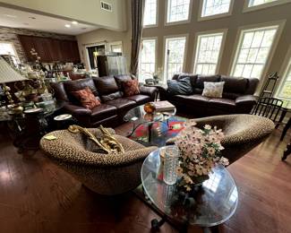 Leather couches, leopard print chairs, various glass-top tables, lighting and home decor