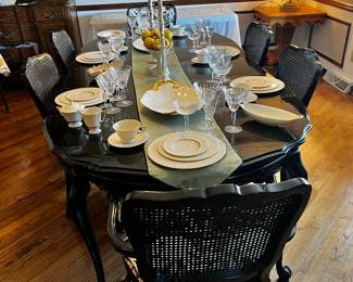 This formal dining room table and chairs is stunning! The table is expanded in this photo to its largest length. The measurements expanded is 91" c 48". Each of the three leaves are 14.75" each. The table is a glossy black and has 6 caned back chairs, two have arms. The armed chairs have a lovely floral print with pink flowers, and the four armless chairs have pink velvet cushions.