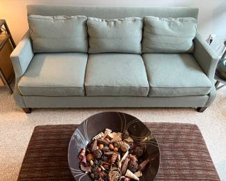Mint green upholstered couch. Brown upholstered ottoman. Brown decorative bowl.