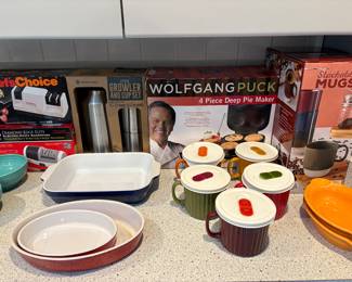 New in box Wolfgang Puck 4-Piece pie mater. New in box set of four stackable mugs. New in Box knife sharpening set. New in box growler and cup set. Colorful baking and serving dishes. Liquid bowls with tops.