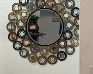 A contemporary decorative wall mirror with concentric metal rings