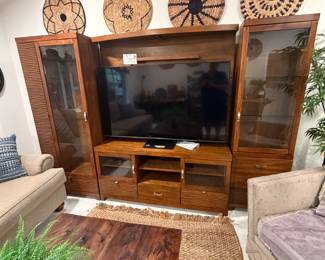 A large entertainment center, distinctive wood coffee table, and a side chair with matching ottoman complete the living room’s stylish setup.