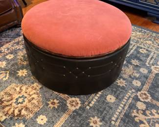 round upholstered ottoman with a dark base and a coral-colored top
