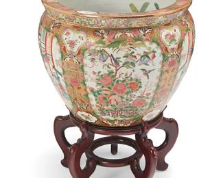 1404
A Chinese Rose Medallion porcelain fish bowl
20th century
The underside with an apocryphal reign mark for Qianlong Period (1735-1796) stamped in red and an applied sticker: Made in China
The exterior with alternating friezes depicting courtly figural scenes or garden landscapes, featuring butterfly motifs to floral and filigree borders, the interior decorated with fish figures, set on a carved wood stand
Porcelain: 15.25" H x 20" Dia.; Stand: 10.5" H x 17" Dia.
Estimate: $200 - $400